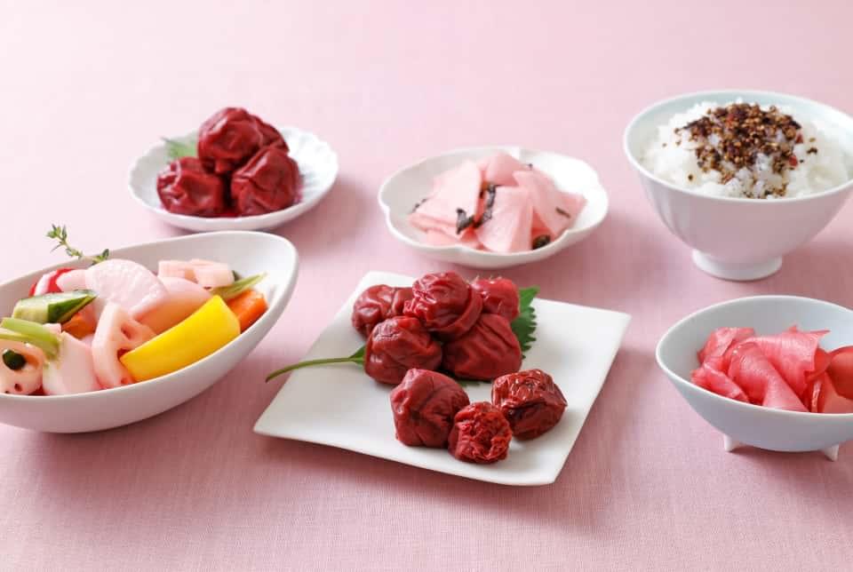 梅酢を活用したらでぃっしゅぼーやオリジナルの「野菜なんでもピクルスの素（もったいない赤梅酢）」＝写真左前　は、どんな野菜でも切って入れるだけの手軽な合わせ調味料。淡いピンク色に、酸っぱ可愛く漬かります。食卓に出すだけの大根のお漬物やガリなど、一品あると嬉しいお惣菜も開発しました。もみ紫蘇を活用したふりかけは、風味がよくついご飯をおかわりしたくなる味わいです＝写真右奥